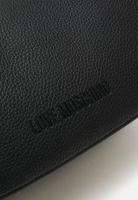 Borsa in pelle sintetica nera con texture, caratterizzata dal logo "LOVE MOSCHINO" in rilievo in un design discreto. Superficie liscia con una finitura a grana fine.