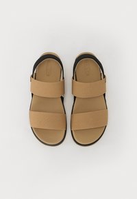 Beige sandaler med to brede stoffstropper og en svart bakstropp. Teksturert innersåle og glatt gummisåle.