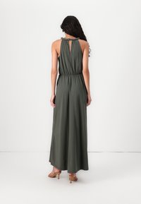Vestido maxi verde-oliva com design sem mangas, cintura franzida e detalhe com recorte nas costas. Tecido suave com um caimento descontraído.