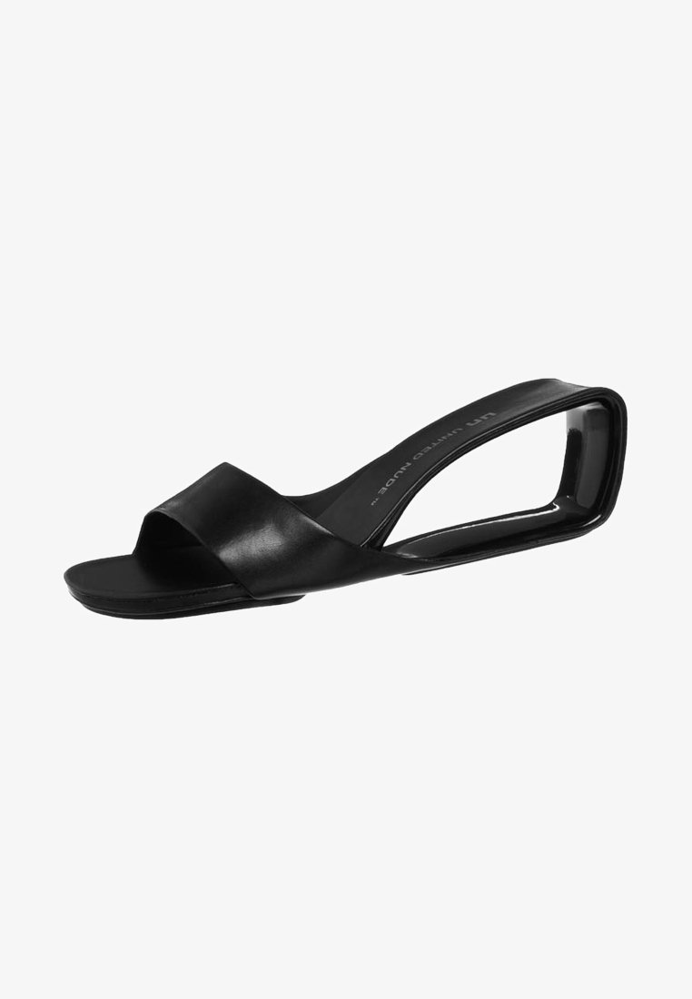 Mule noire à bout ouvert avec une large bride en cuir et un talon distinctif incurvé en boucle.
