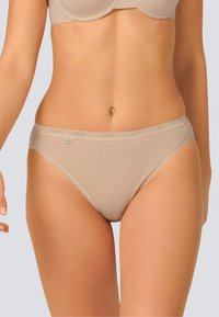 Le mutande beige in cotone presentano un design senza cuciture con un delicato bordo lungo l'elastico in vita e le aperture delle gambe. Texture morbida, senza ulteriori motivi o decorazioni.