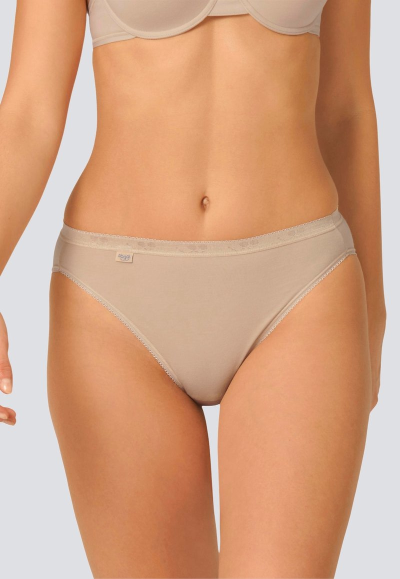 Le mutande beige in cotone presentano un design senza cuciture con un delicato bordo lungo l'elastico in vita e le aperture delle gambe. Texture morbida, senza ulteriori motivi o decorazioni.