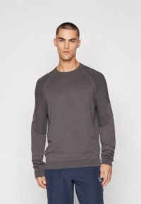 Mørkegrå langermet genser med ribbede detaljer på skuldrene, rund hals og tettsittende mansjetter. Stoffet har en glatt tekstur.