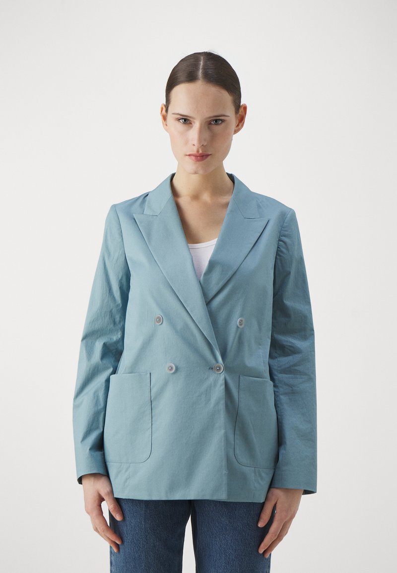 Blazer doppiopetto azzurro chiaro realizzato in tessuto liscio, con due tasche frontali e bottoni rotondi, dotato di colletto strutturato e maniche lunghe.