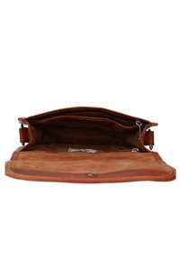 Tan leather bag with a zipper opening, featuring a spacious interior, soft texture, and a brass hardware accent. Lined with suede.