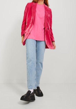 Blazer di velluto rosa sopra una t-shirt rosa, abbinato a jeans azzurri chiari e scarpe platform nere chunky, con una vestibilità rilassata.