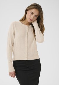 Cárdigan de punto beige con escote redondo, mangas largas y cierre de botones. Presenta una tela texturizada y puños acanalados.