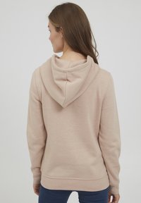 Ljusrosa hoodie i mjukt material. Har en avslappnad passform, dragsko i huvan och ribbade muddar och fåll. Enkla design utan mönster.