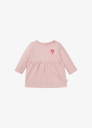 Lichtroze jurk met lange mouwen en een gerimpelde taille, voorzien van een kleine rode hartborduursel op de borst en knoopdetails op de schouder.