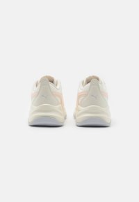Puma footwear with a white and light pink design, featuring a cushioned sole, textured upper, and subtle logo accents on the heels.