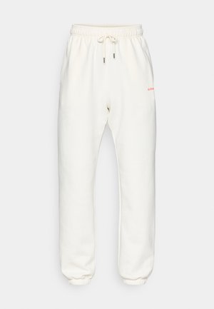 Pantaloni della tuta bianchi in pile con vita elastica e cordino. Presentano tasche laterali e un piccolo logo rosso sul davanti.