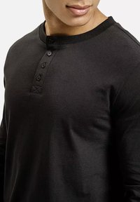 Czarna koszula z długim rękawem i okrągłym dekoltem, z zapięciem na guziki i prążkowanymi mankietami. Gładki materiał bawełniany.