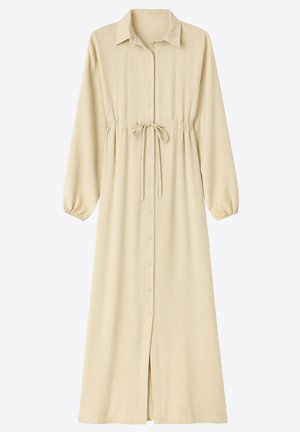 Long, beige shirt dress with a collared neckline, button closure, and an adjustable waist tie; features gathered sleeves and a front slit.