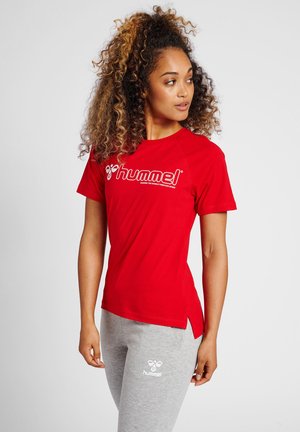 Rød kortærmet t-shirt med hvid "hummel" logo, med rund halsudskæring og sideslidser; parret med grå joggingbukser med et logo.