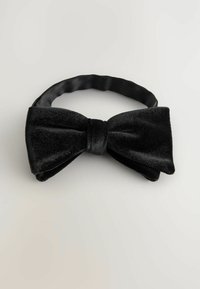 Black velvet bow tie with a smooth texture and a central knot, attached to a fabric band. Suitable for formal occasions.