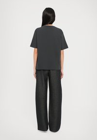 Kulkolegrå oversized t-shirt med korte ærmer, parret med brede grå bukser, begge i glat stof og minimalistisk design.