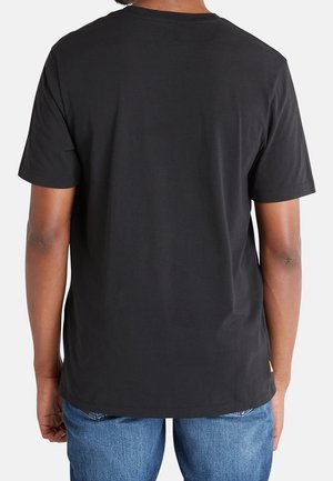 T-shirt en coton noir avec un col rond, des manches courtes et une texture lisse. Pas de logos ni de motifs visibles. Porté avec un jean bleu.