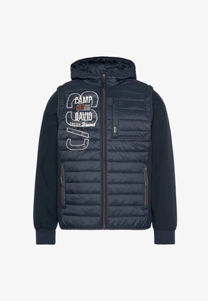 Gewatteerde marineblauwe jas met een capuchon, voorzien van geborduurde tekst, ritszakken en contrasterende stof op de mouwen en onderrug.