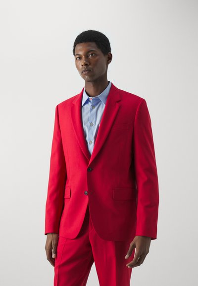 Rød jakkesæt med notch-lapel og enkelt knaplukning, parret med en lyseblå skjorte. Glat stof, slim-fit design.