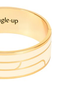 Bracelet en métal doré avec une surface lisse, incrustation en émail blanc et lignes courbées sculptées pour les accents de design. Logo gravé à l'intérieur.