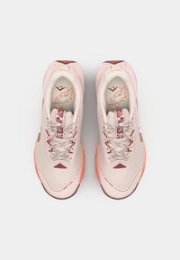 Hellrosa Sportschuhe mit einem strukturierten Mesh-Obermaterial, grauen Akzenten, kontrastierenden Schnürsenkeln und einer orangen Laufsohle, die ein Kartenmotiv auf der Innensohle aufweist.