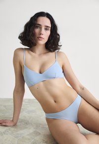 Light blue bikini set featuring a bralette top with thin straps and a low-rise bottom; smooth texture and minimalist design.