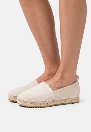 Espadrilles en suède beige avec semelle en jute, présentant un design à enfiler et un bout arrondi et plat. Design minimaliste sans quincaillerie.