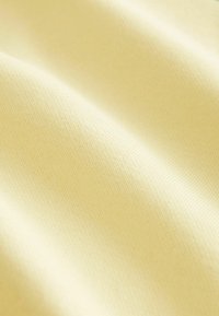 Hellgelber Stoff mit einer glatten Textur und einem feinen, gleichmäßigen Gewebemuster, das subtile Unterschiede in Farbnuancen und Licht aufweist.