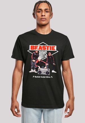 Black cotton t-shirt featuring a graphic print of three musicians with a boombox, labeled "Beastie Boys" and "Solid Gold Hits" in bold colors.