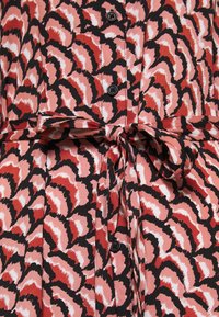 Robe à motifs rouges et roses avec un design abstrait noir, dotée d'un devant boutonné, d'un col et d'une ceinture nouée à la taille. Texture du tissu douce.