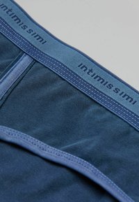 Niebieskie bawełniane bokserki z miękkim pasem w talii, na którym w niebieskim kolorze widnieje napis "intimissimi". Materiał jest gładki z subtelną fakturą i detalami w szwach.