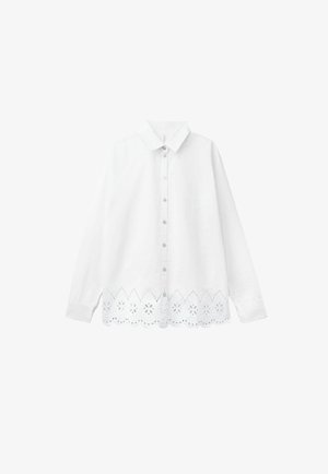 Biała koszula z długim rękawem zapinana na guziki, z klasycznym kołnierzykiem i falistym koronkowym dołem z kwiatowymi wycięciami.