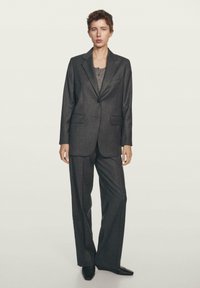 Mørkegrå skræddersyet jakkesæt med en enkelt-knap blazer, brede bukser og en struktureret grå top. Glat stof og klassisk design.