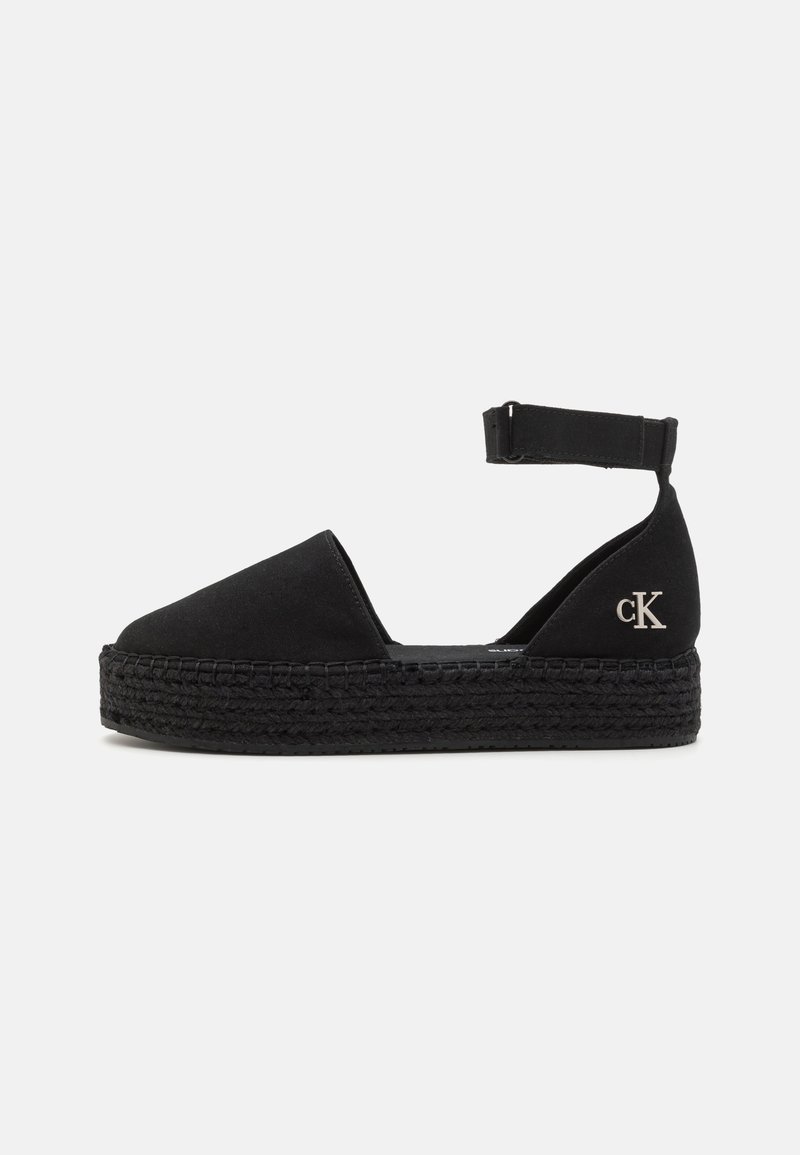 Espadrille noire avec un bout rond et une bride de cheville. Comprend une semelle en jute noir tressé texturé et un petit logo argenté.