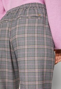 Plaid trousers with an elastic waistband, featuring shades of gray, pink stripes, and subtle texture. Includes a small back pocket detail.