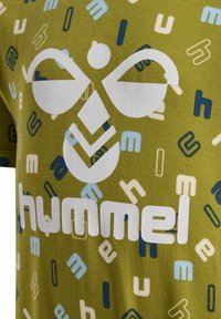 Olivgrön T-shirt med en vit logotyp och flerfärgade bokstäver i blått och krämfärgat. Mjuk tyg med ett mönstrat design och rundad halsringning.