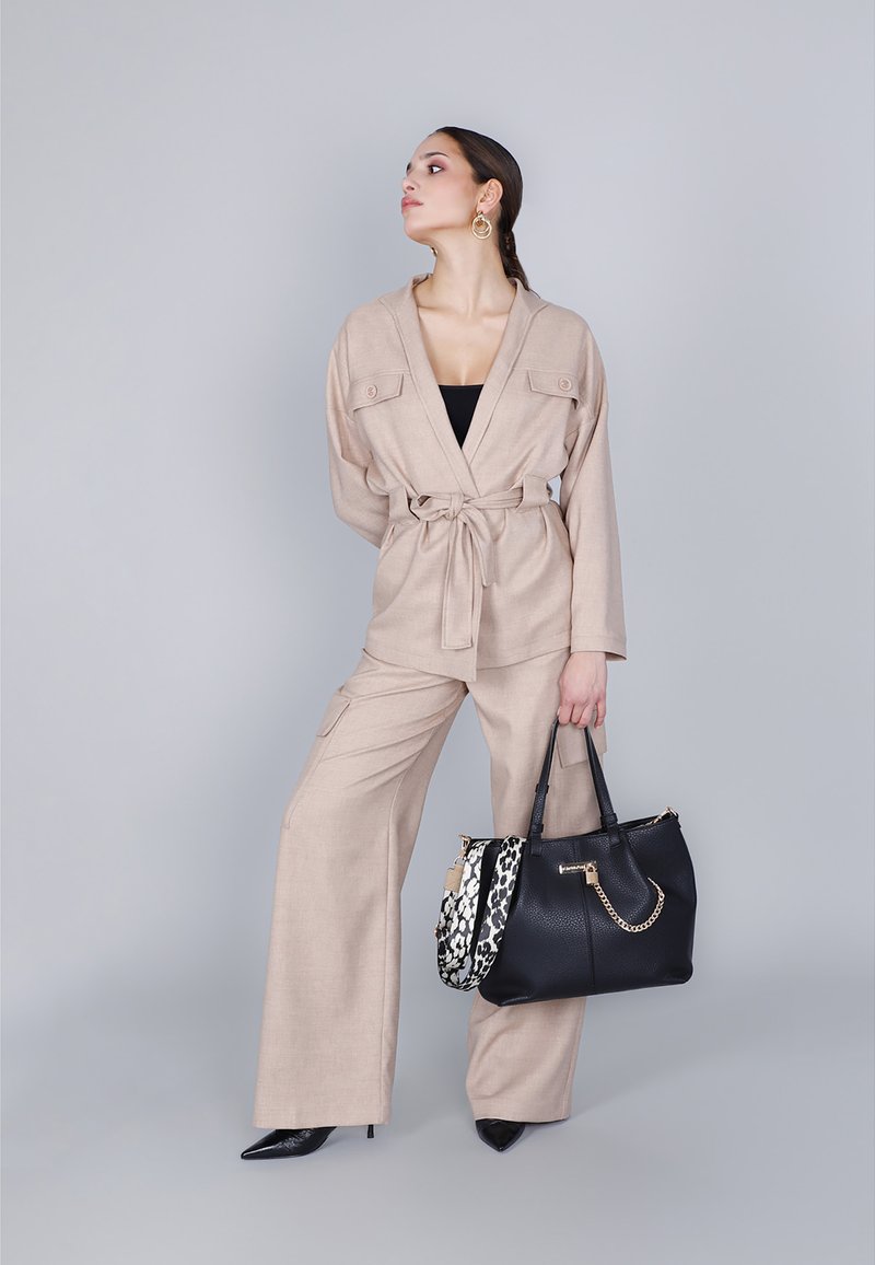 Beige skräddarsydd blazer och vida byxor med bälte, ihop med en svart läderhandväska med kedjedetalj och djurmönstrad rem.