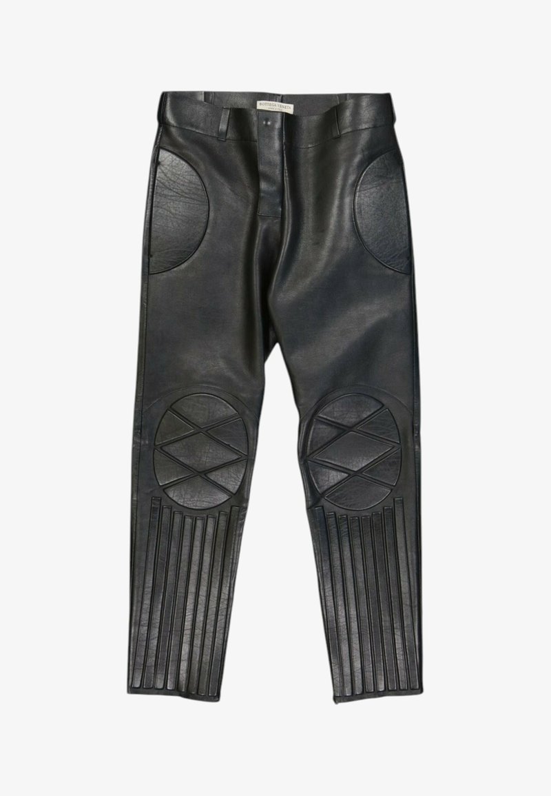 Pantalon en cuir noir avec des détails rembourrés circulaires et rectangulaires aux genoux et sur le bas des jambes, passants de ceinture et fermeture éclair avant.