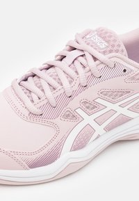 Ljust rosa träningssko med en texturerad plastöverdel, mesh-element, vita detaljer och mönstrade dekorationer längs sidorna och snörena.