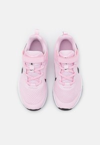 Scarpe da ginnastica rosa con tomaia in rete, lacci elastici e cinturino in velcro. Presentano il logo Nike nero sui lati e una suola bianca.