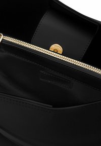 Borsa a tracolla nera in pelle con zip color oro, texture liscia e chiusura circolare interna. Presenta un design minimalista e cuciture delicate.