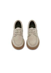 Μπεζ σουέντ παπούτσια με δύο οπές, ραμμένη λεπτομέρεια στο δάκτυλο και λαστιχένιες σόλες. Διαθέτουν λεία υφή και στρογγυλεμένο σχήμα.