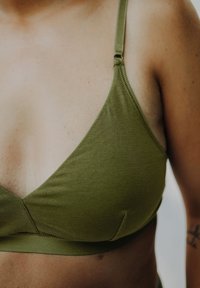 Olive green bralette with a smooth texture, triangular cups, thin adjustable straps, and a subtle seam detail along the edges.
