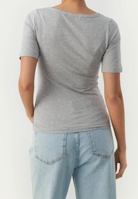 Grijze kortekijk t-shirt van zachte stof, met een ronde halslijn en een getailleerde snit, gecombineerd met lichtblauwe hoge taille jeans.