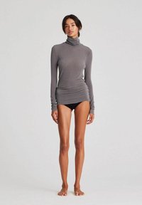 Maglione grigio a maniche lunghe con collo a imbuto, dal design raffinato e strutturato. Presenta dettagli arricciati in vita, un tessuto morbido e una silhouette aderente.