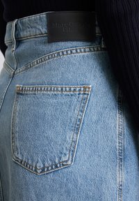 Hellblaue Denim-Jeans mit einem Lederpatch auf der Rückseite, das "Marc O'Polo DENIM" beschriftet ist. Verfügt über auffällige Nähte und eine Gesäßtasche.