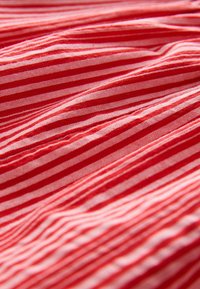 Czerwono-biała materiał w paski z nawet plecieniami i gładką teksturą, z wąskimi i szerokimi paskami tworzącymi dynamiczny wzór.