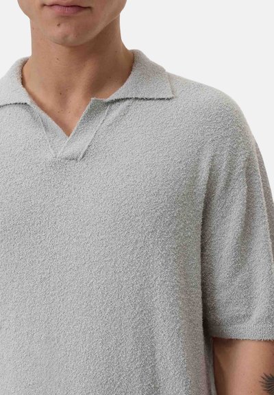 Polo shirt grigio chiaro realizzato in tessuto testurizzato, con colletto corto e design senza bottoni, caratterizzato da una vestibilità rilassata.