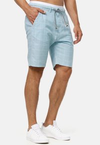 Lichtblauwe geruite shorts van katoenmix, met een trekkoord in de taille en zijzakken. Gecombineerd met witte sneakers.