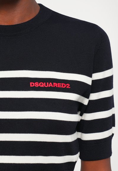 Close-up of navy and white striped knit shirt with red "DSQUARED2" logo embroidered on the chest, worn by a person with dark skin.